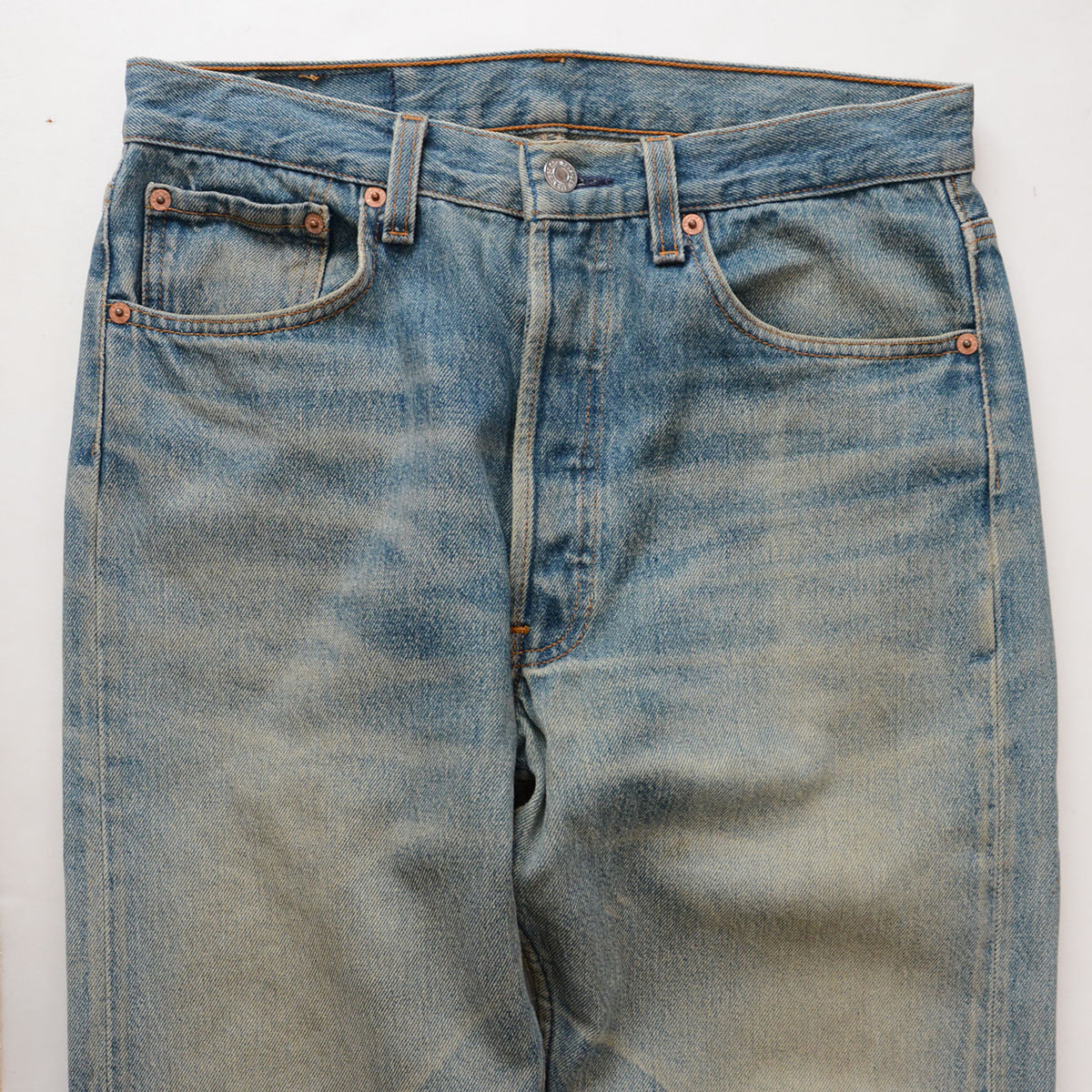 Levi’s 501 faded blue denim with whiskering, copper-tone rivets and discoloration on the thighs