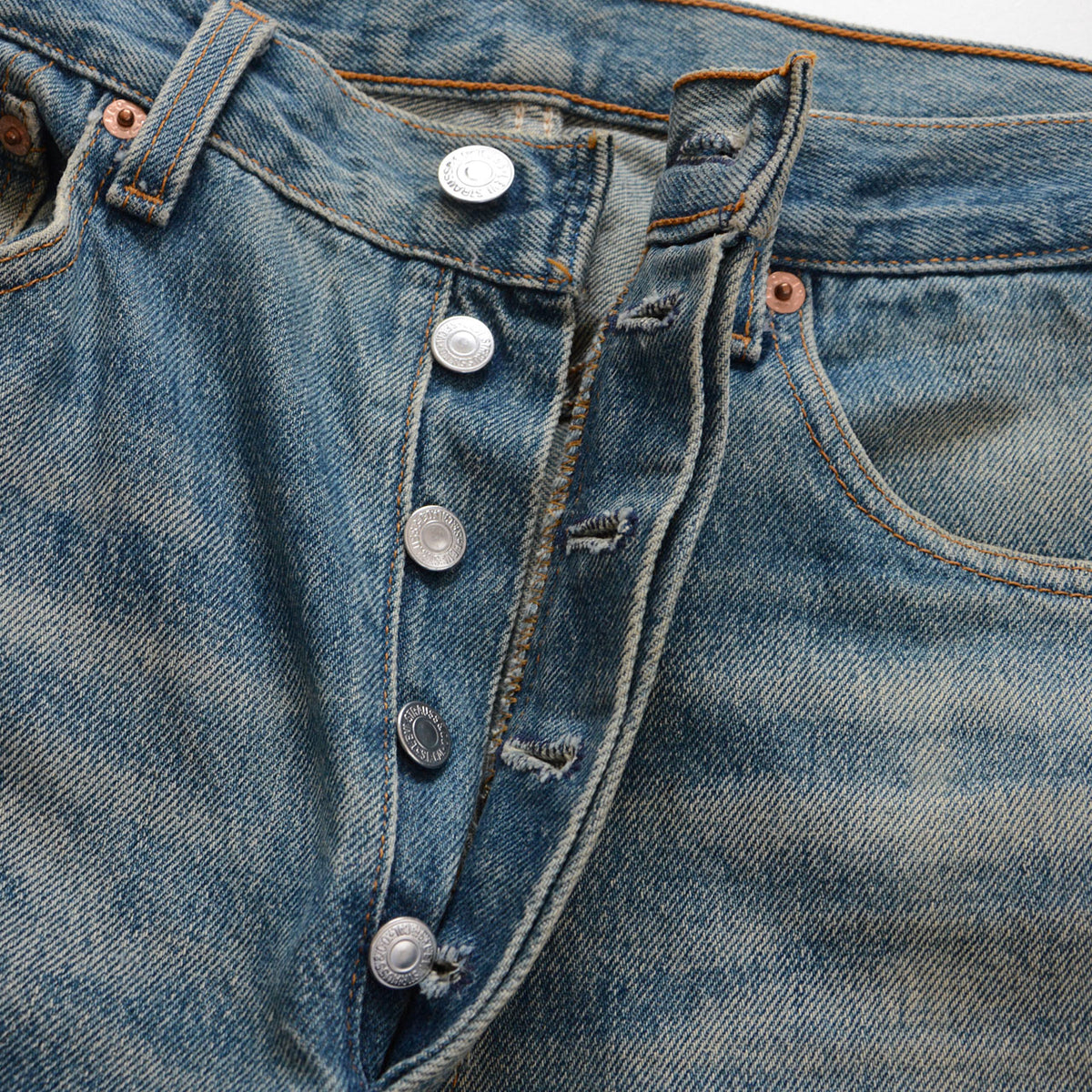Levi’s 501 blue denim button fly with five metal buttons and fraying around the buttonholes