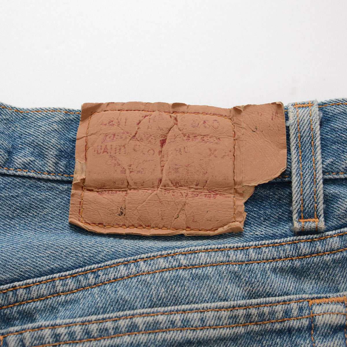 Levi’s waist patch with cracking, missing edges and faded lettering on blue denim