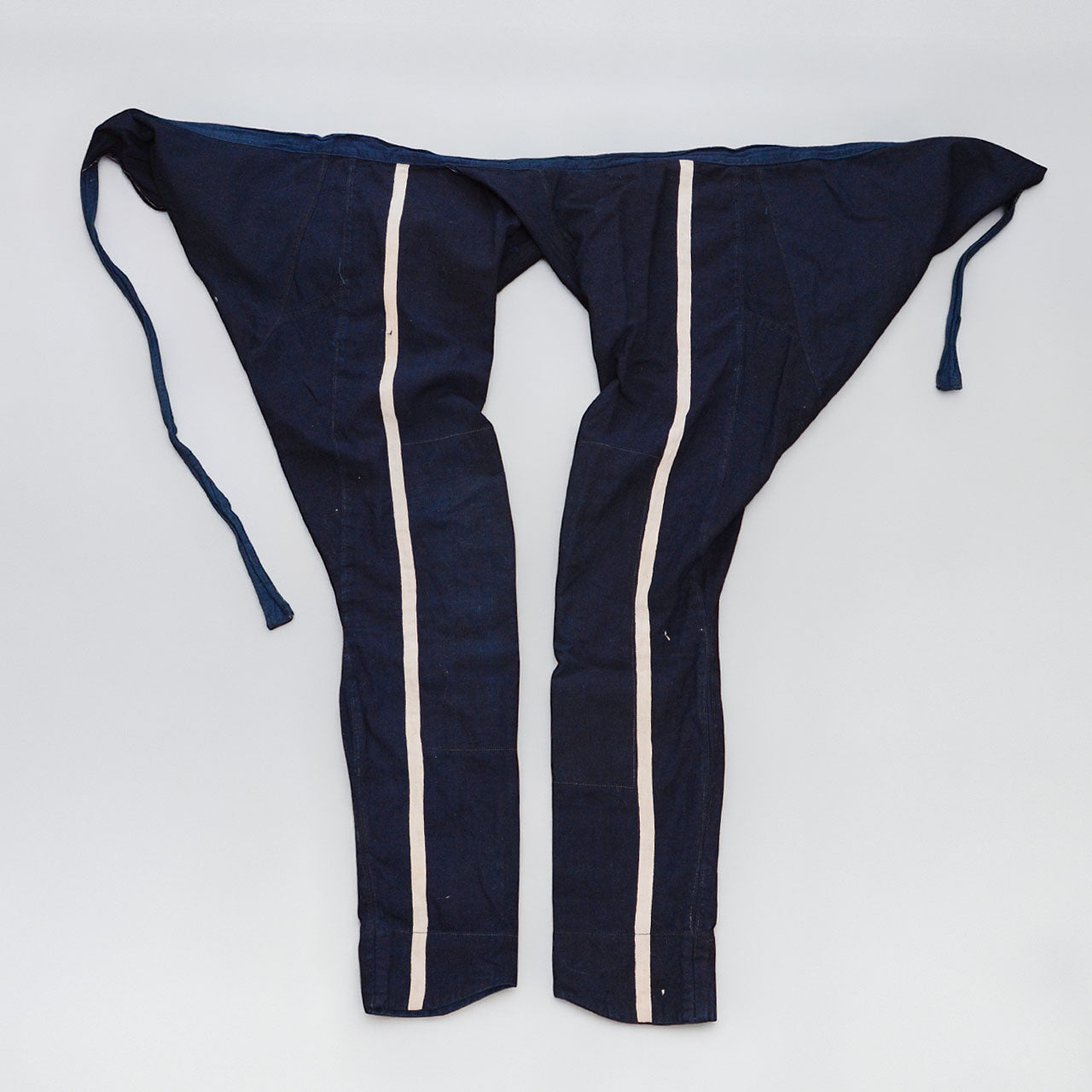 Indigo cotton momohiki laid flat, showing natural-colored stripe detail on both legs