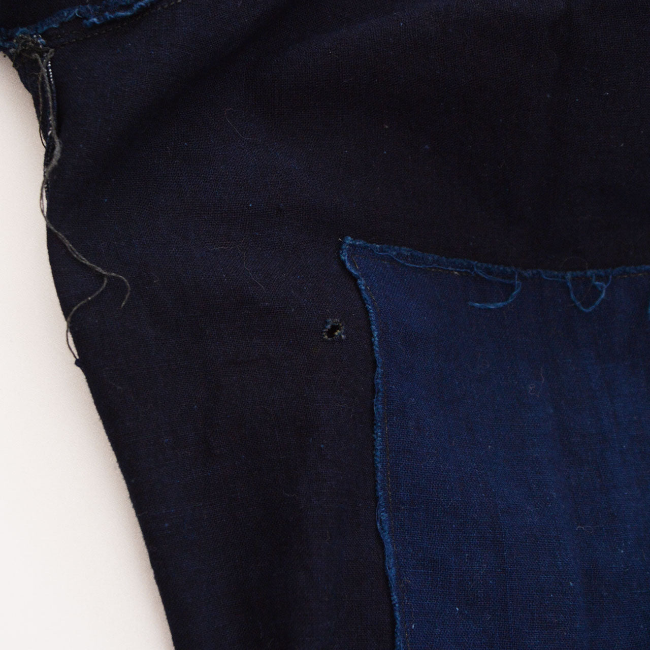 Damage on the indigo cotton fabric near the reinforcement area