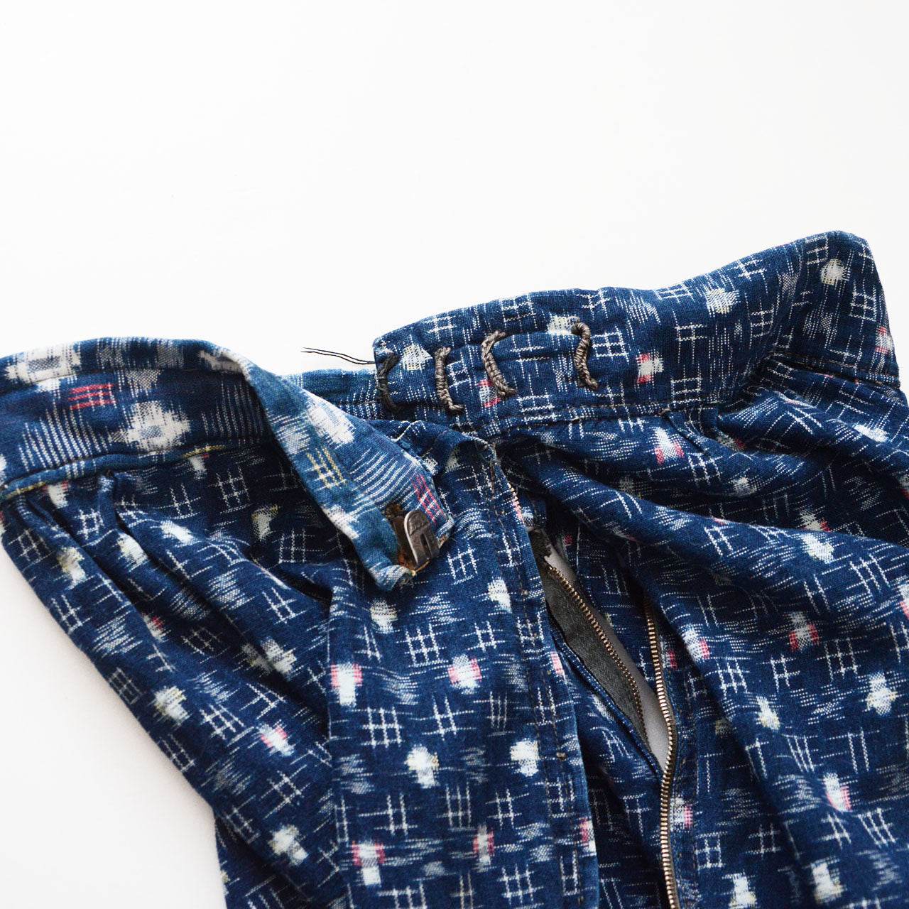 Hook-and-eye waist closure detail on indigo kasuri mompe, aged metal hardware, mid-Showa vintage Japan