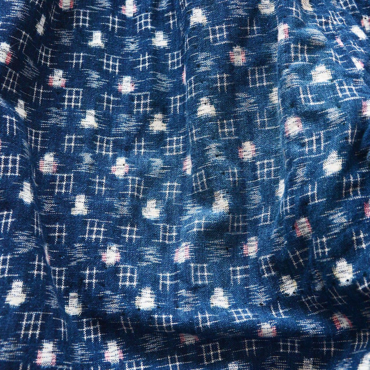 Indigo-dyed kasuri cotton textile, white and pink ikat dot and grid motifs on deep navy ground, handwoven vintage Japanese fabric