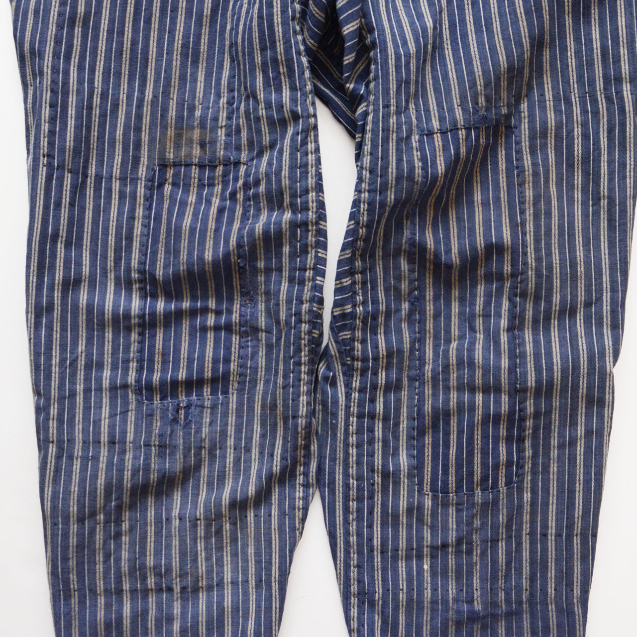 Boro patch repair on front of stripe cotton monpe pants, multiple hand-stitched patches, blue multi-stripe cotton, Tohoku Japan vintage