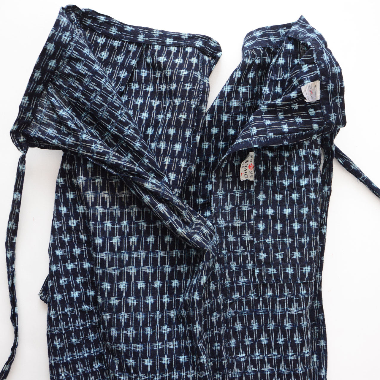 Front and back panels of indigo Bingo kasuri monpe pants separated to show side slits and construction