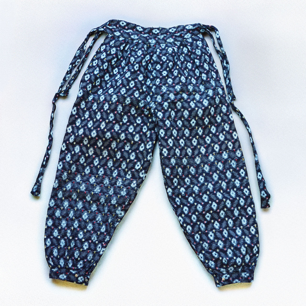 indigo kasuri cotton monpe — relaxed wide-leg silhouette with gathered ankles and side tie cords, back view
