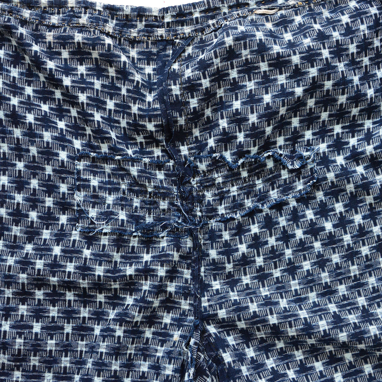 Repair area of indigo kasuri monpe pants, interior view, hand-stitched mend on navy ikat check cotton, Japan vintage
