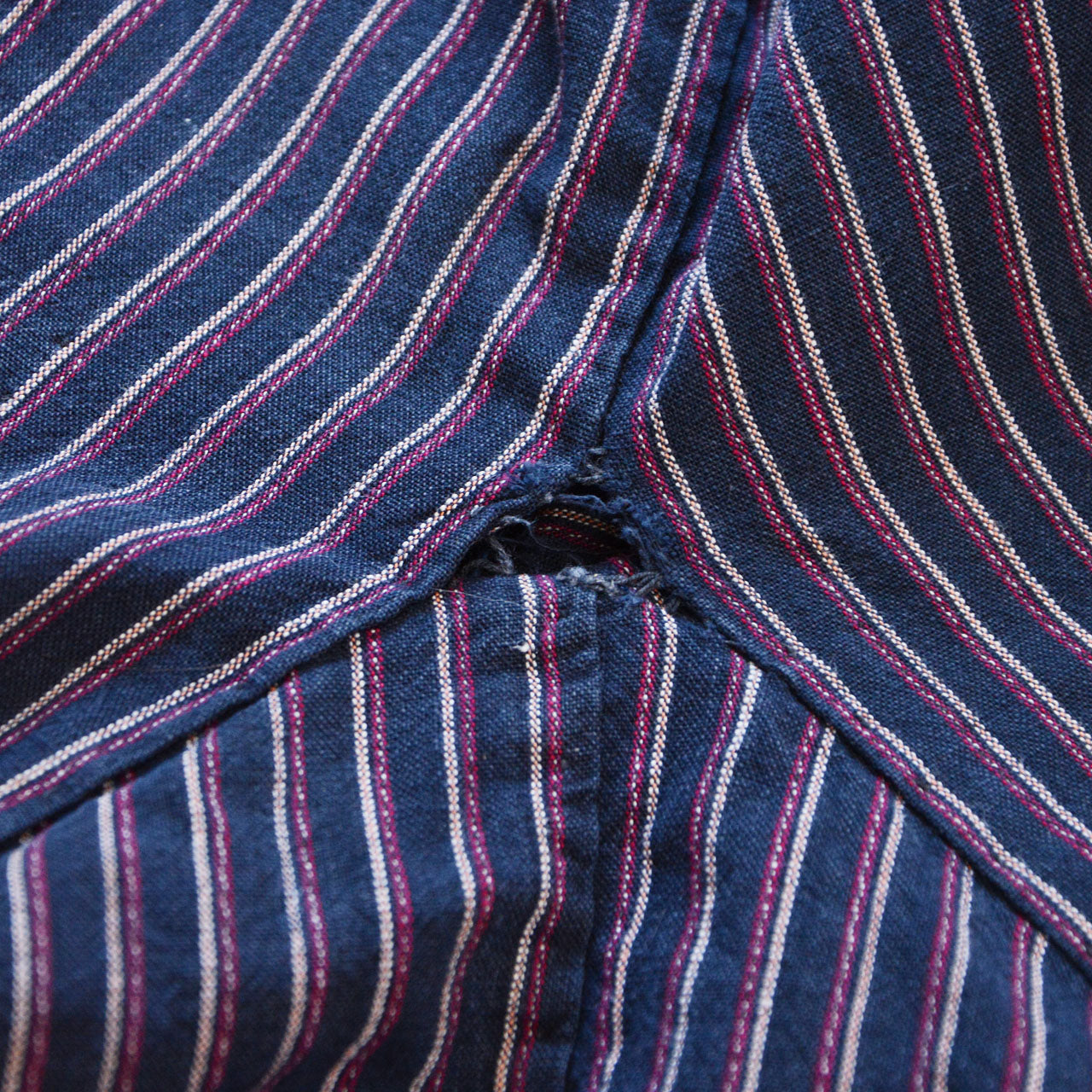 Crotch gusset area showing stitch loss and small hole, vintage Japanese monpe, striped cotton with visible wear and fraying