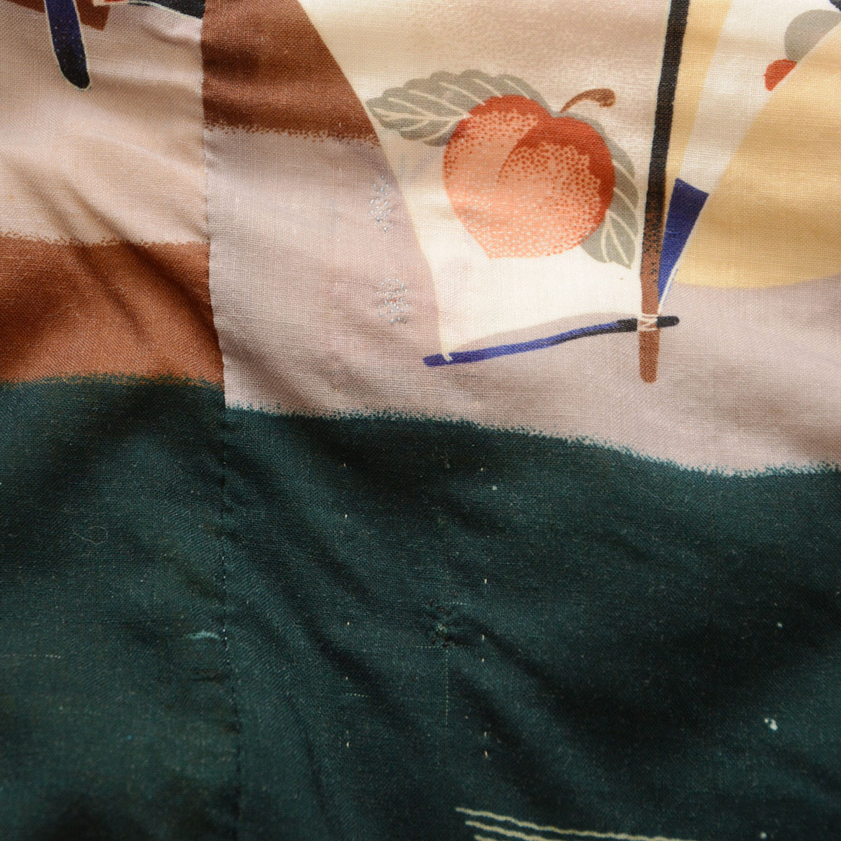 Stitched repairs in the green and beige patterned fabric of a Japanese vintage nagajuban kimono