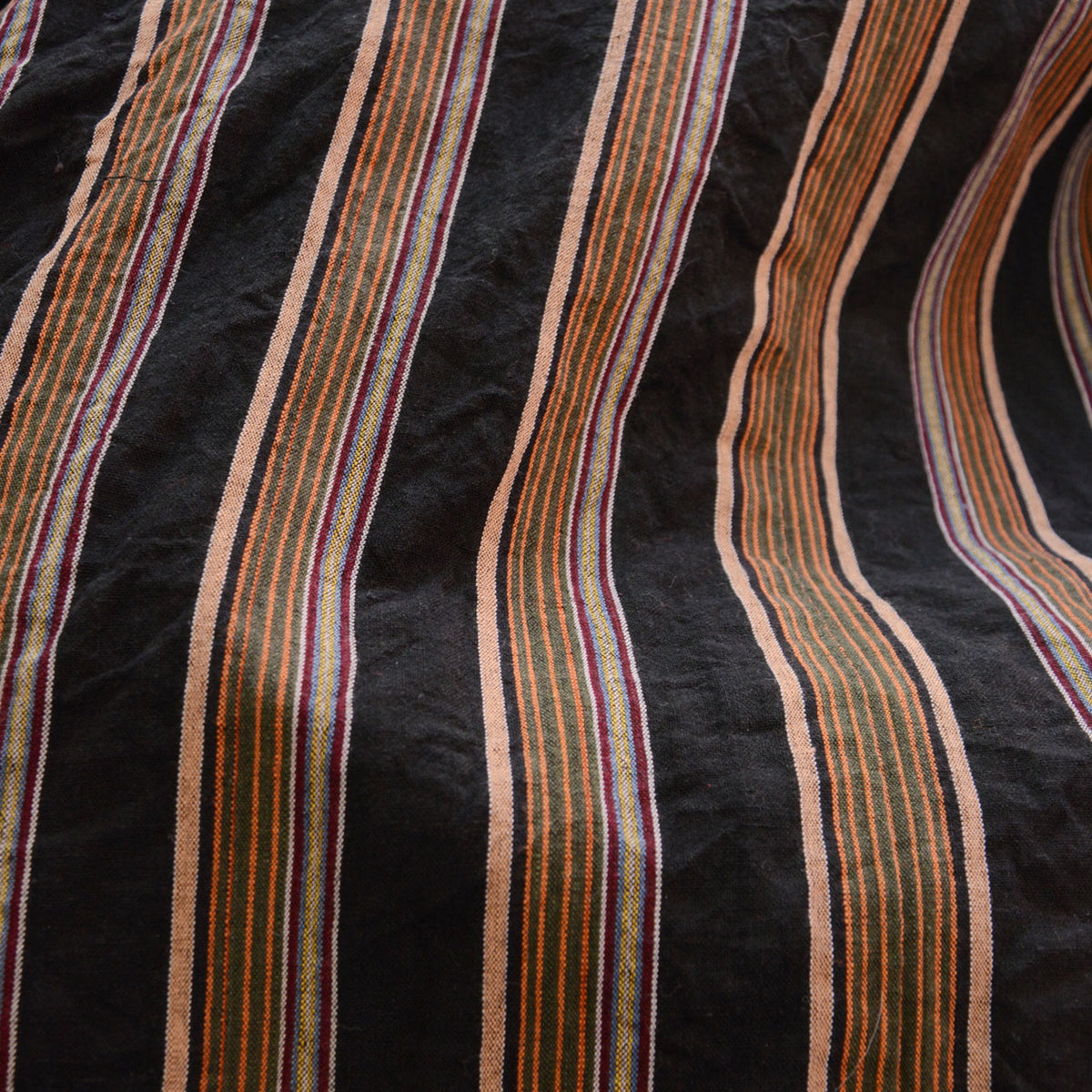 Orange, green and purple-toned stripes woven into black cotton noragi fabric