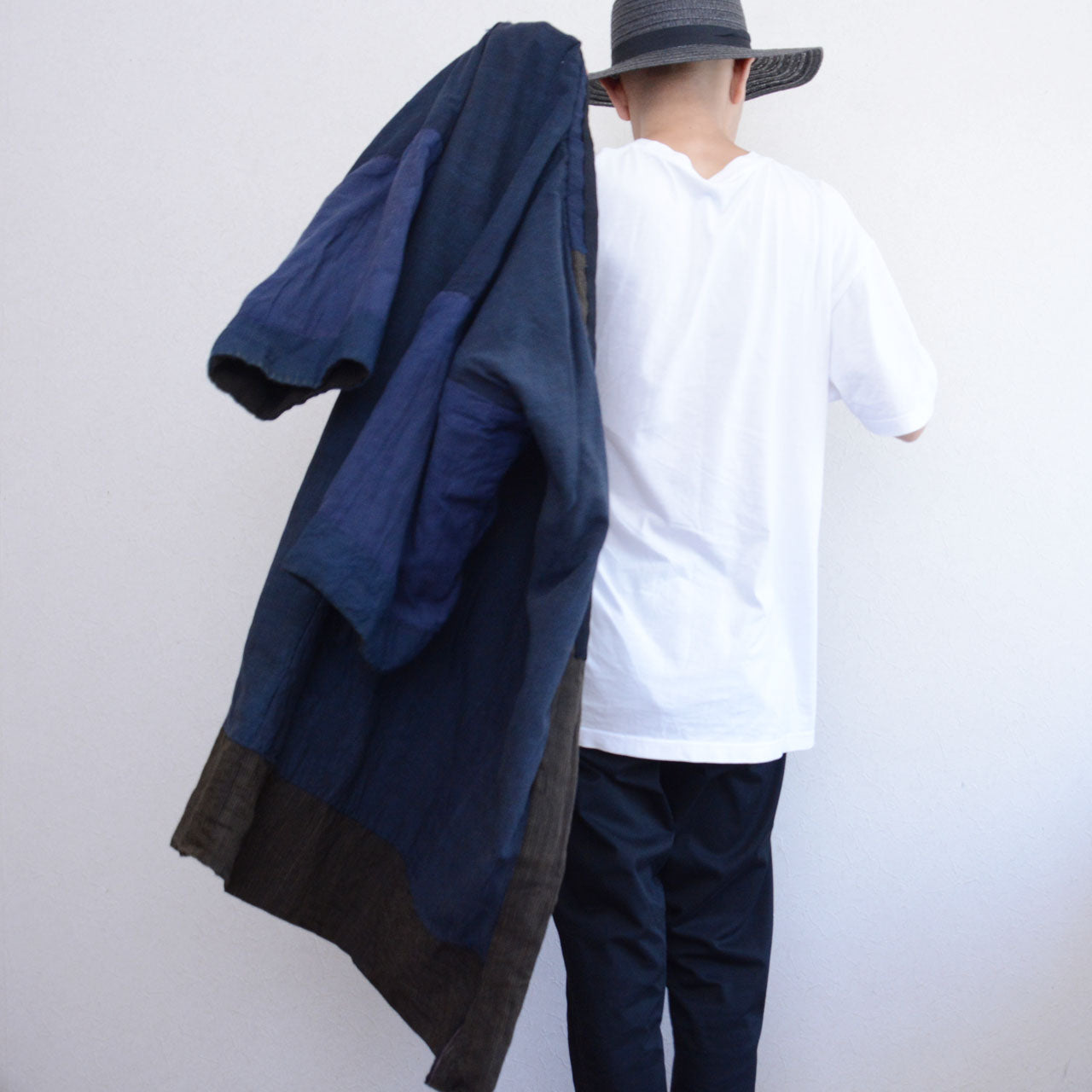Boro noragi jacket, indigo-dyed cotton outer, back view carried over shoulder, striped crazy pattern lining visible, worn with white tee and dark denim, Japan vintage styling, pre-WWII Tohoku