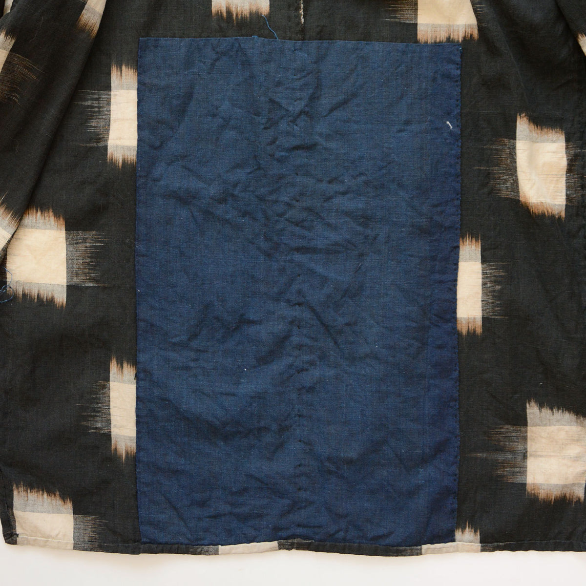 Plain indigo cotton lower lining surrounded by dark fabric with ecru kasuri motifs.