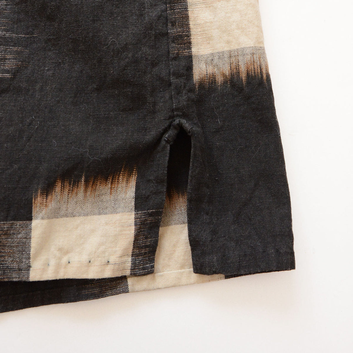 Hem side slit and ecru kasuri pattern on dark vintage cotton fabric.