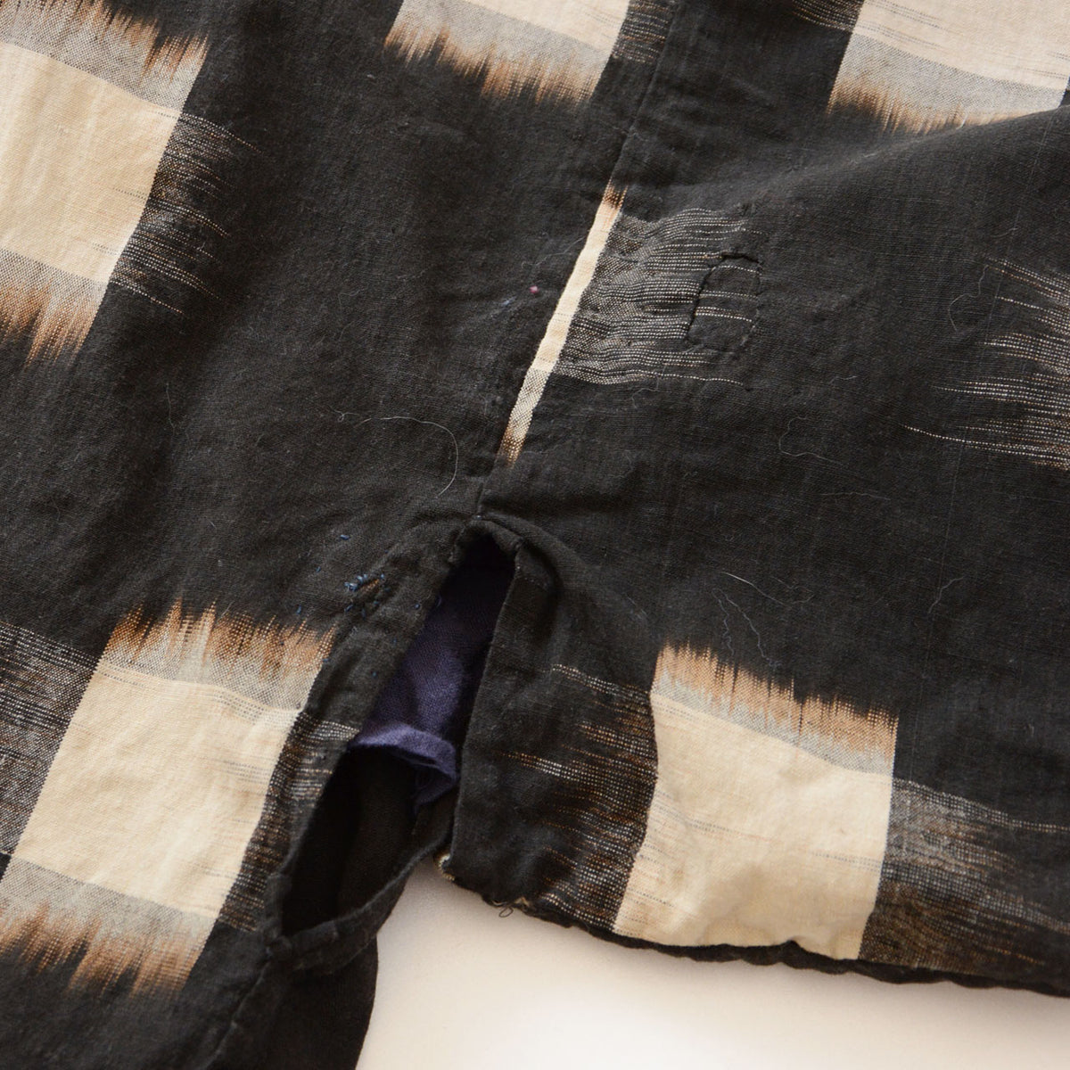 Miyatsuguchi side opening and small repairs in dark cotton with ecru kasuri motifs.