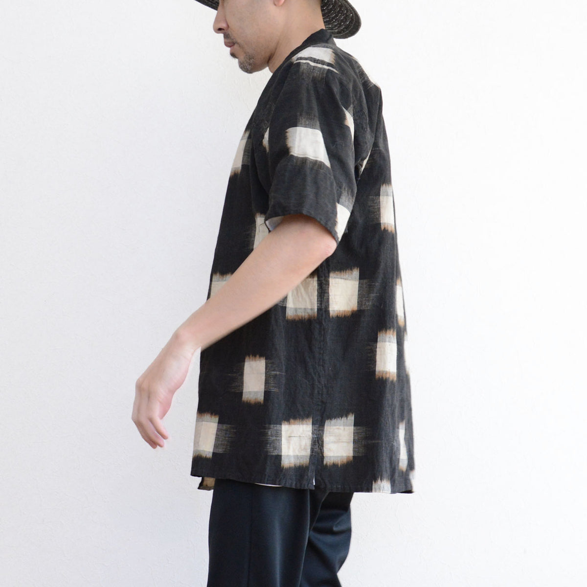 Japanese vintage kasuri noragi with elbow-length sleeves and a hem side slit, with dark trousers.