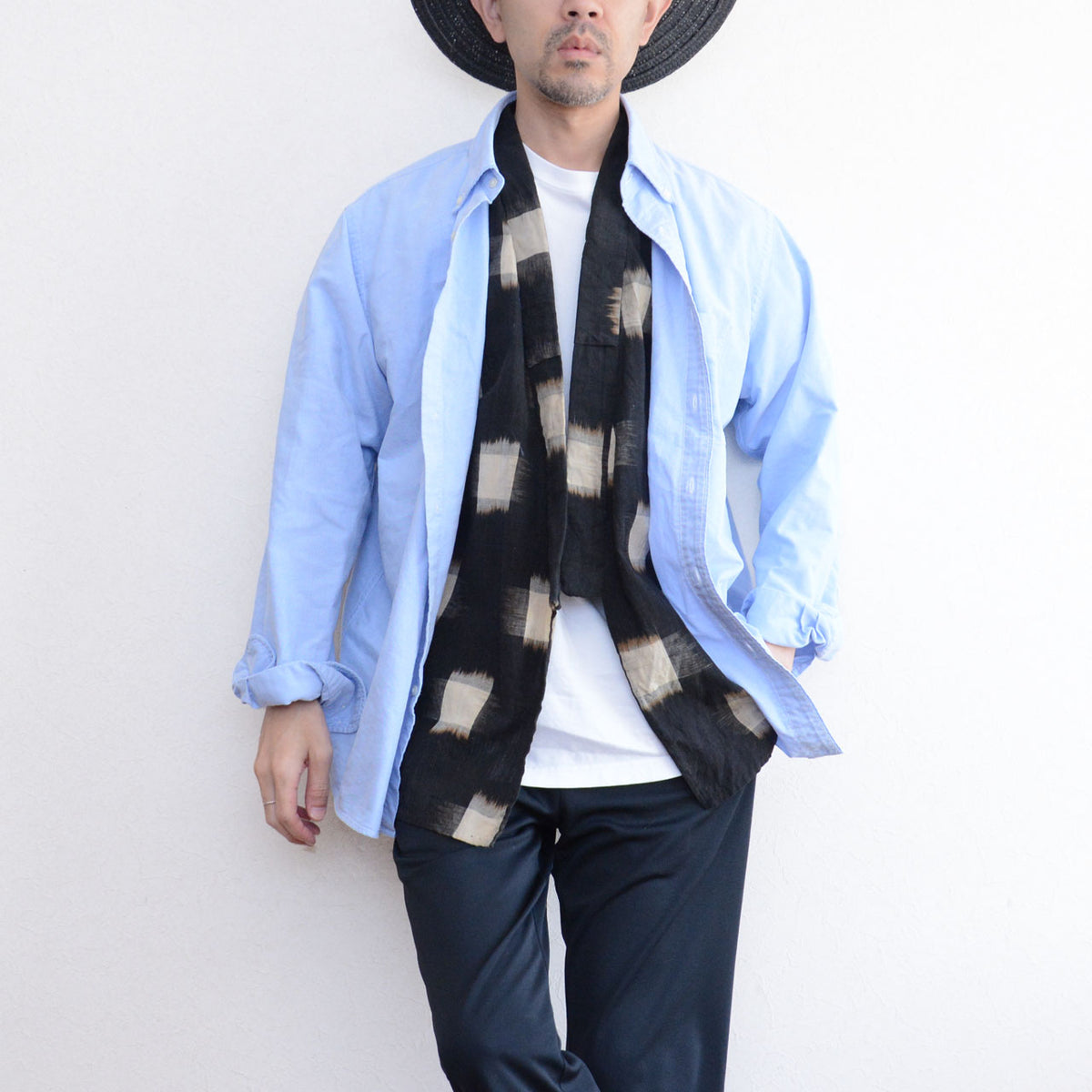 Ecru kasuri-patterned cotton noragi beneath a light blue Oxford shirt, with a white T-shirt and dark trousers.
