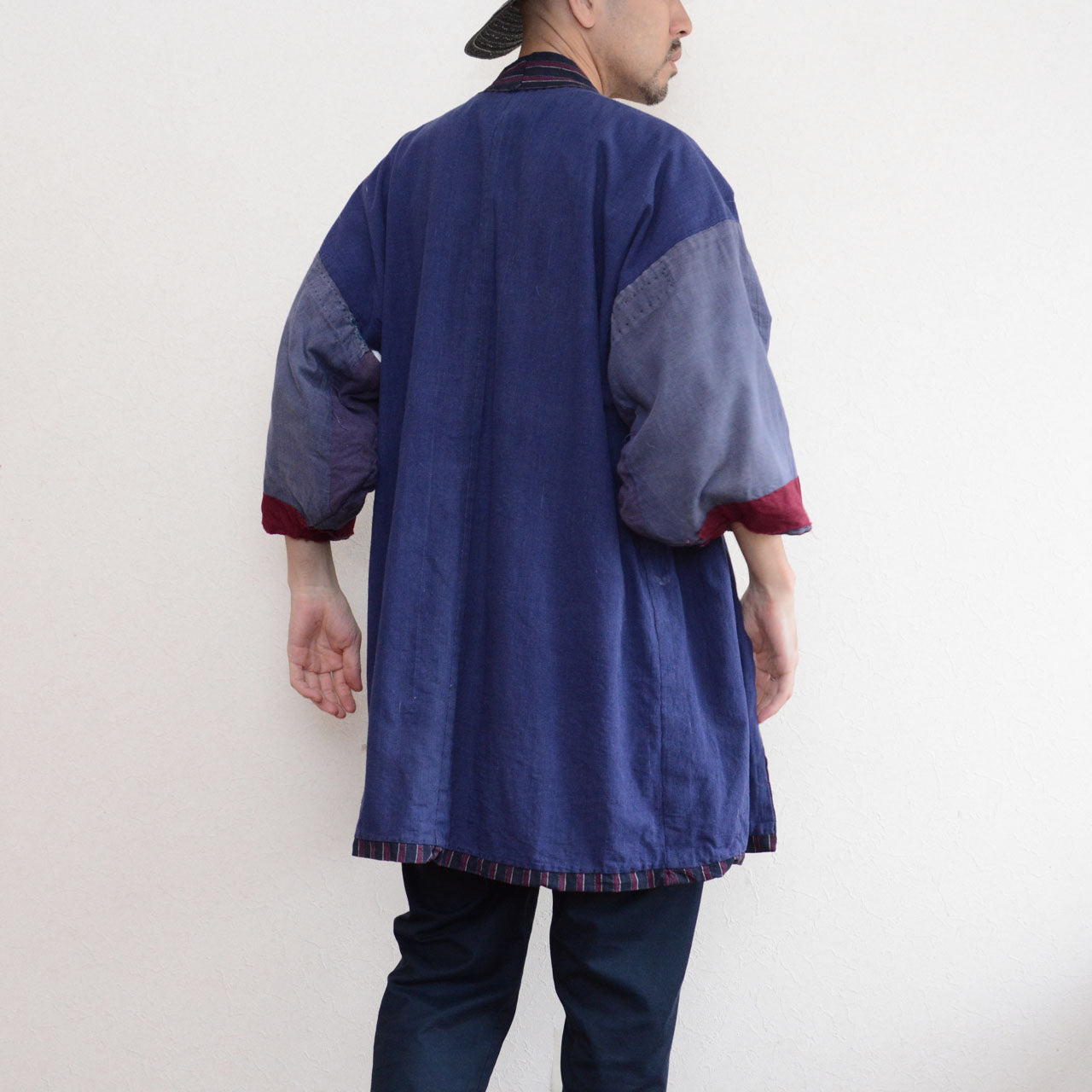 Back view of a model wearing a vintage Japanese noragi with a blue body, grey-blue sleeves, red cuffs, and striped hem