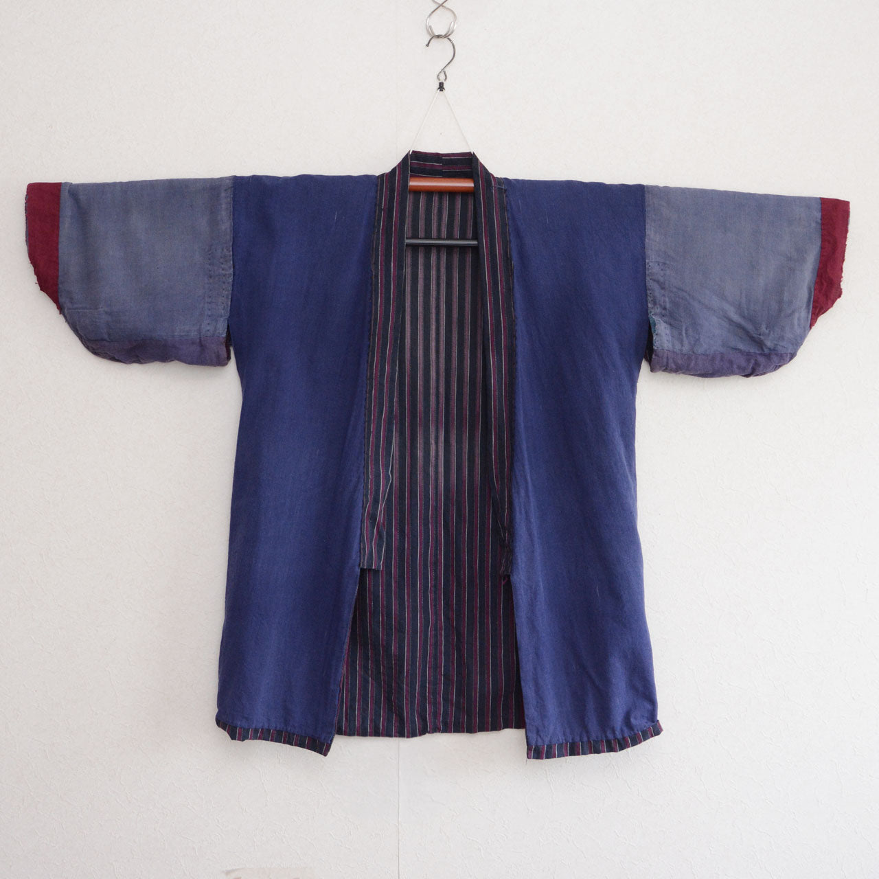 Reverse side of a vintage Japanese cotton noragi opened to show blue inner fabric and striped construction