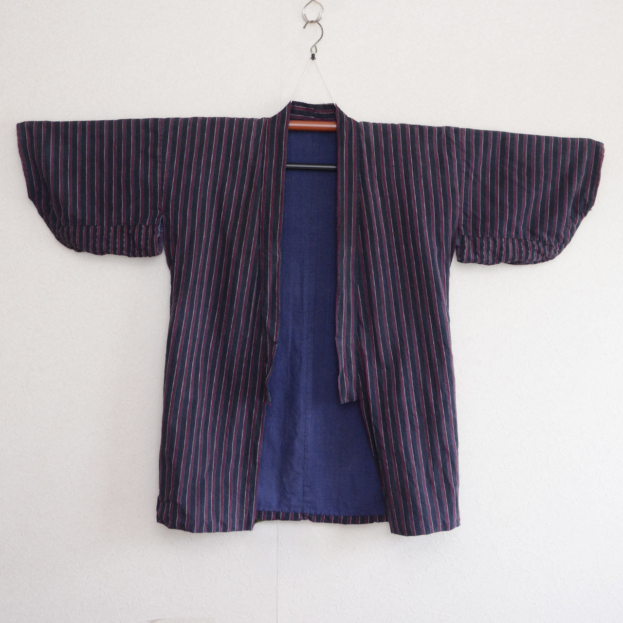 Surface of a vintage Japanese noragi with a blue body, grey-blue sleeves, and red sleeve ends