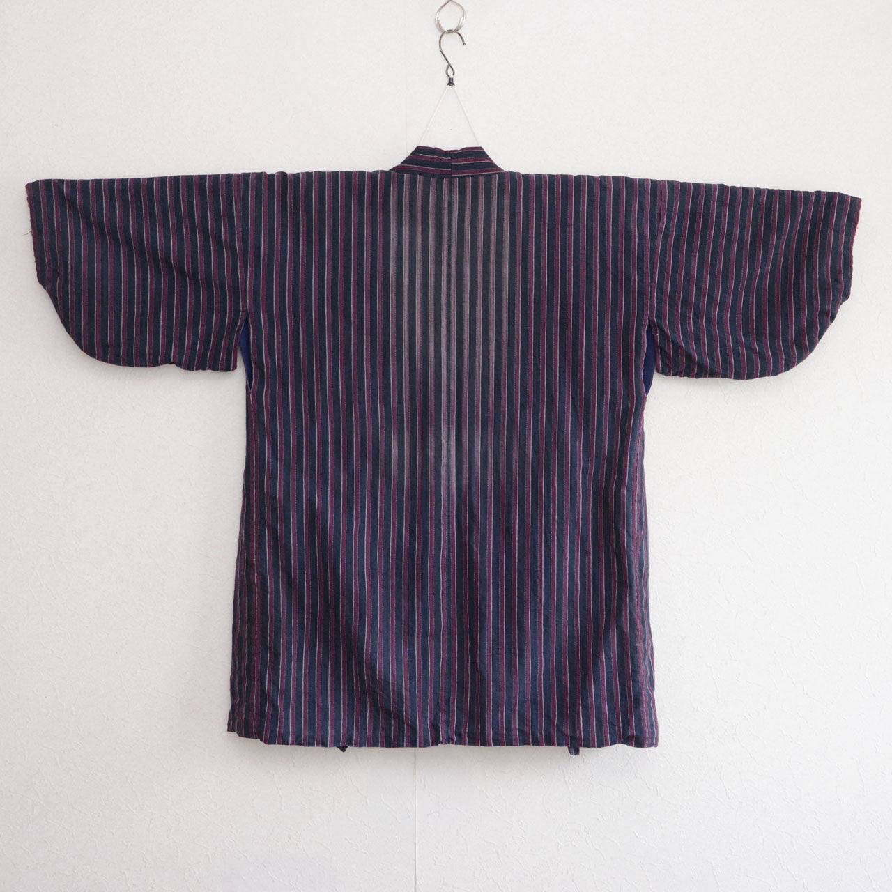 Surface of a vintage Japanese noragi with striped collar and hem, grey-blue sleeves, and red sleeve ends
