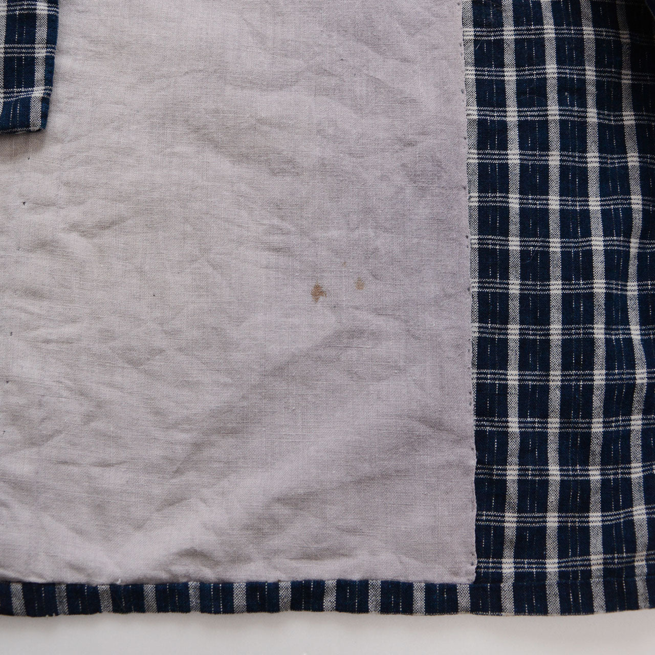 Faded lining of a vintage noragi jacket — aged white cotton with natural discoloration, indigo check outer fabric visible at edge, early Showa era Japan vintage