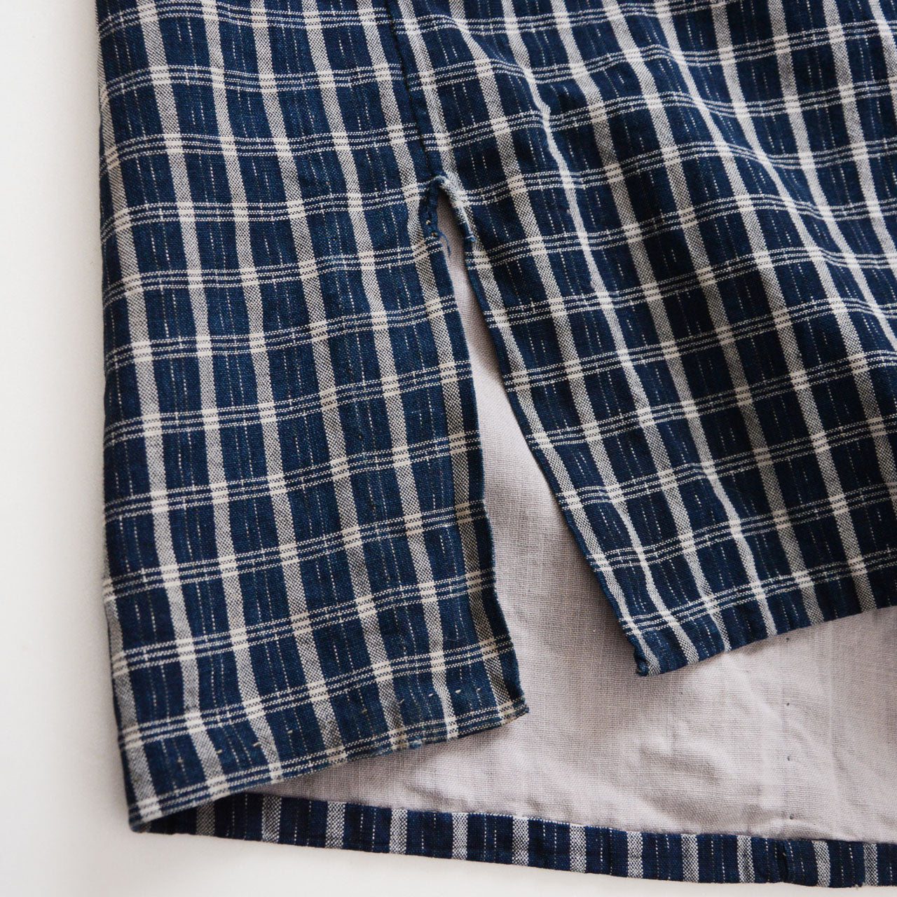 Hem slit detail of a vintage noragi jacket — indigo-dyed cotton check with hand-stitched finish, early Showa era Japan vintage