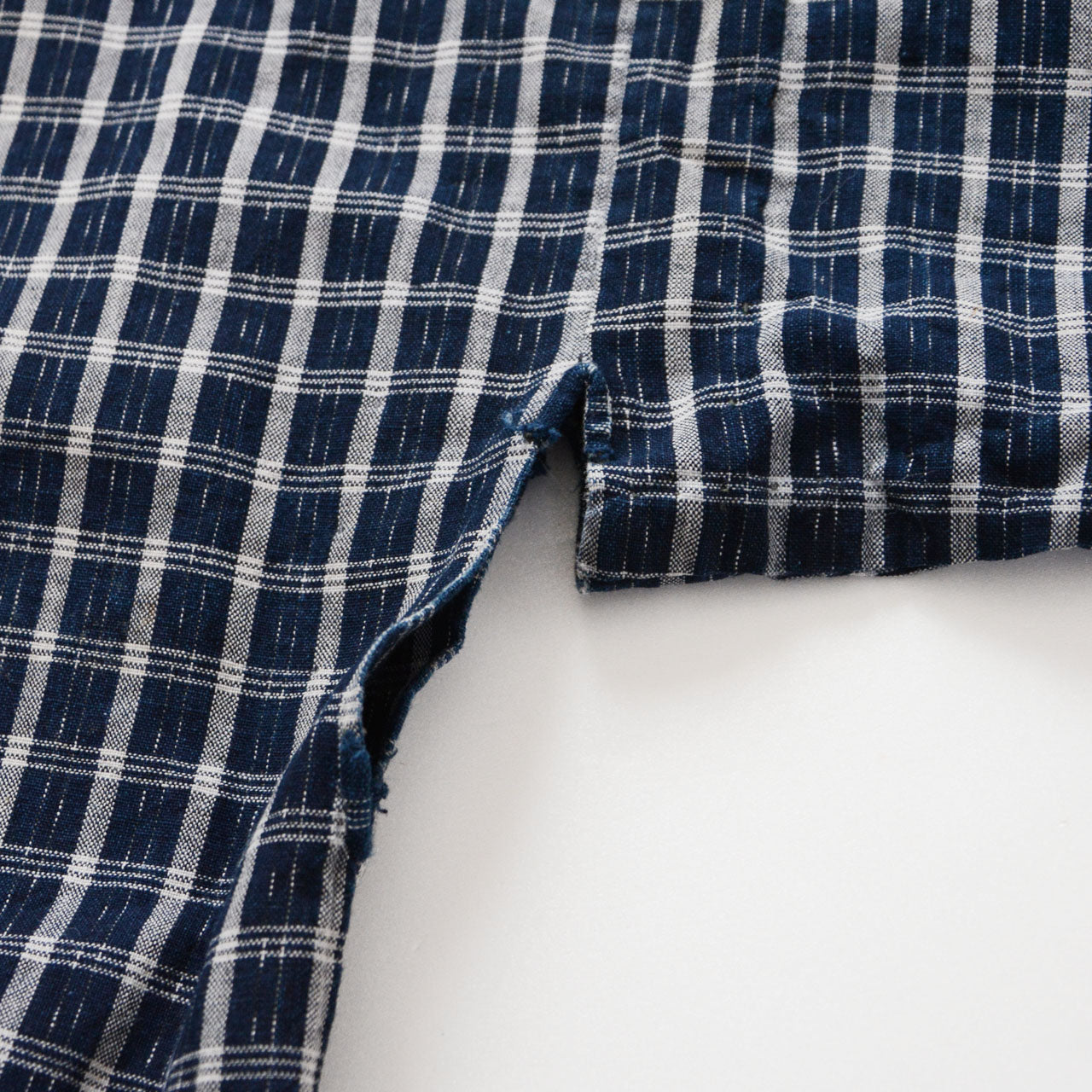 Miyatsuguchi opening of a vintage noragi jacket — indigo check cotton with hand-stitched edge and contrasting inner fabric, early Showa era Japan vintage