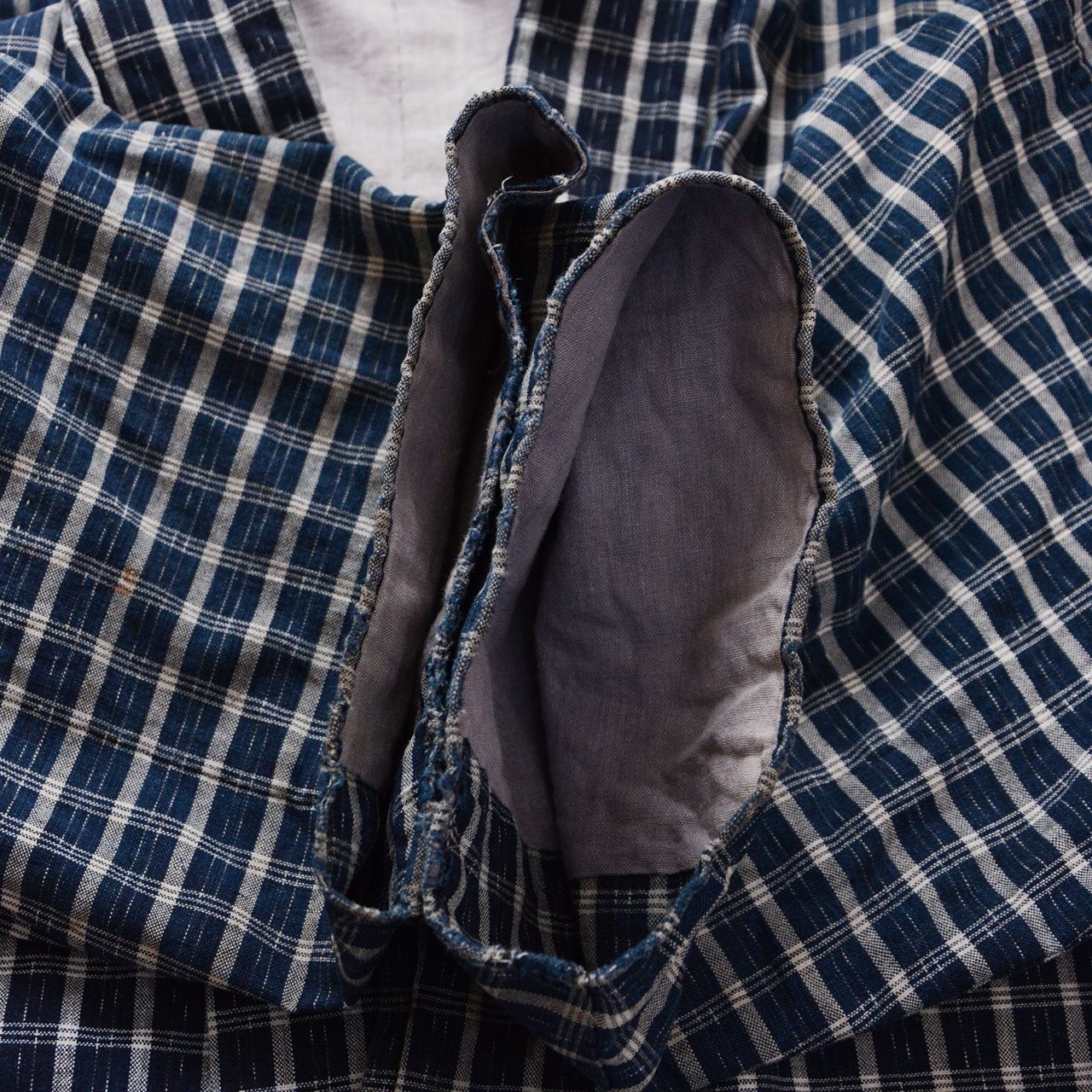 Cuff edge of a vintage noragi jacket — indigo-dyed cotton check with natural fraying and aged damage, early Showa era Japan vintage