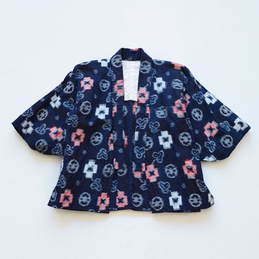 Indigo-dyed cotton noragi jacket, e-gasuri ikat weave, navy ground with multi-motif kasuri pattern in white and red, laid flat front view, Japan vintage