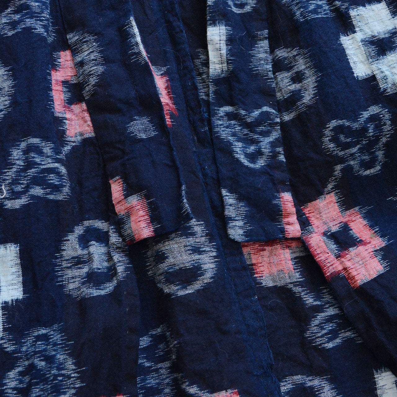 Indigo-dyed cotton noragi jacket, e-gasuri ikat weave, navy ground with multi-motif kasuri pattern in white and red, lower collar detail, Japan vintage