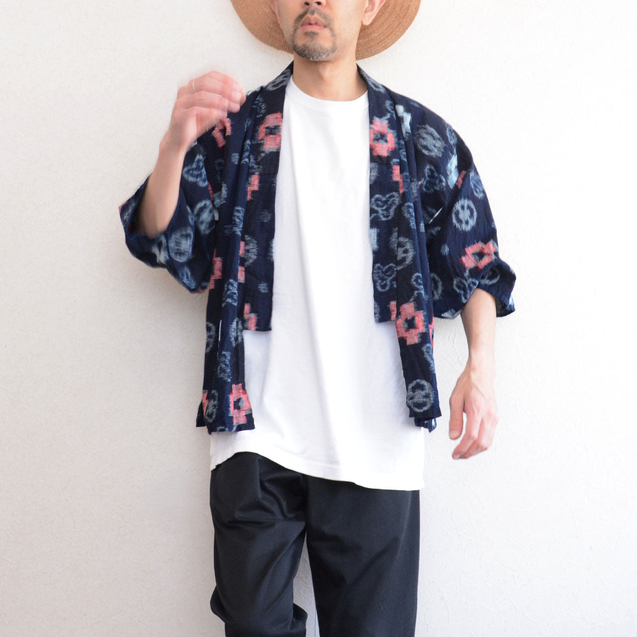 Indigo-dyed cotton noragi jacket, e-gasuri ikat weave, navy ground with multi-motif kasuri pattern in white and red, worn over white tee and black trousers, front view, Japan vintage