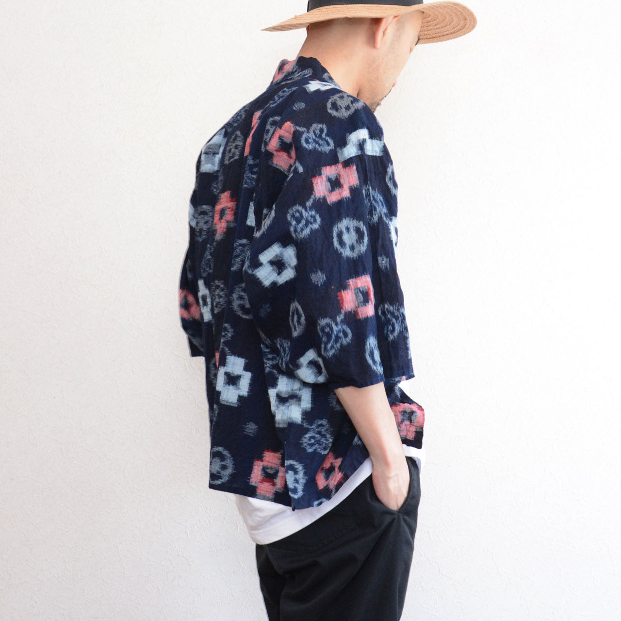 Indigo-dyed cotton noragi jacket, e-gasuri ikat weave, navy ground with multi-motif kasuri pattern in white and red, worn over white tee and black trousers, back view, Japan vintage