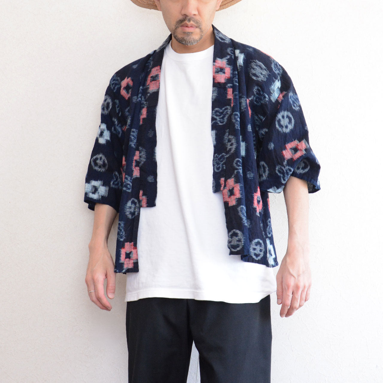 Indigo-dyed cotton noragi jacket, e-gasuri ikat weave, navy ground with multi-motif kasuri pattern in white and red, worn open over white tee and black trousers, front view, Japan vintage