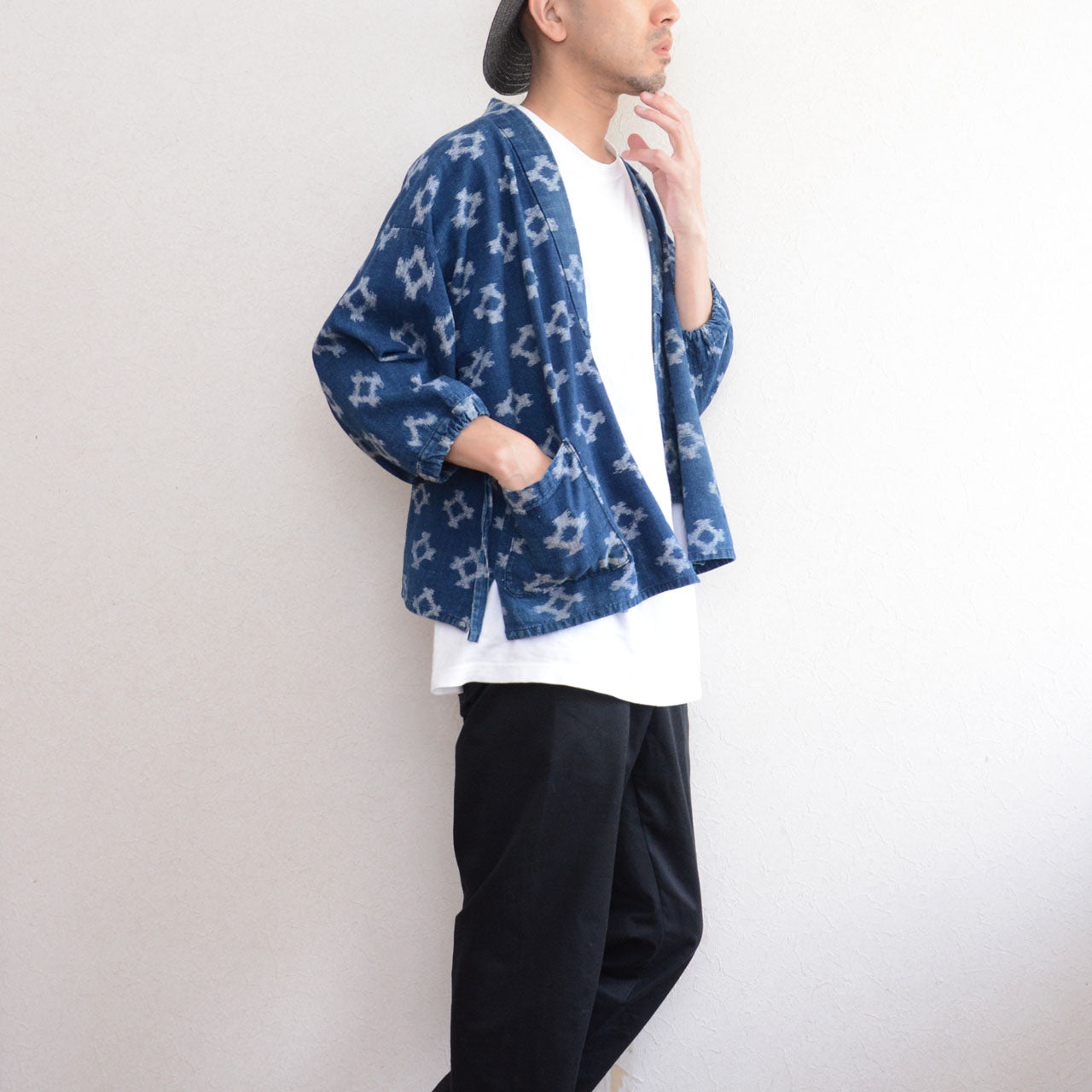 Model wearing indigo kasuri noragi jacket over white t-shirt with hand in pocket, upper body to knee, slow fashion Japan vintage