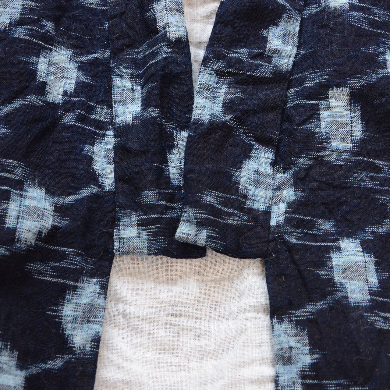 Front opening detail, indigo kasuri noragi jacket, navy cotton ikat pattern, natural cotton lining, hand-sewn construction, Showa era Japan vintage