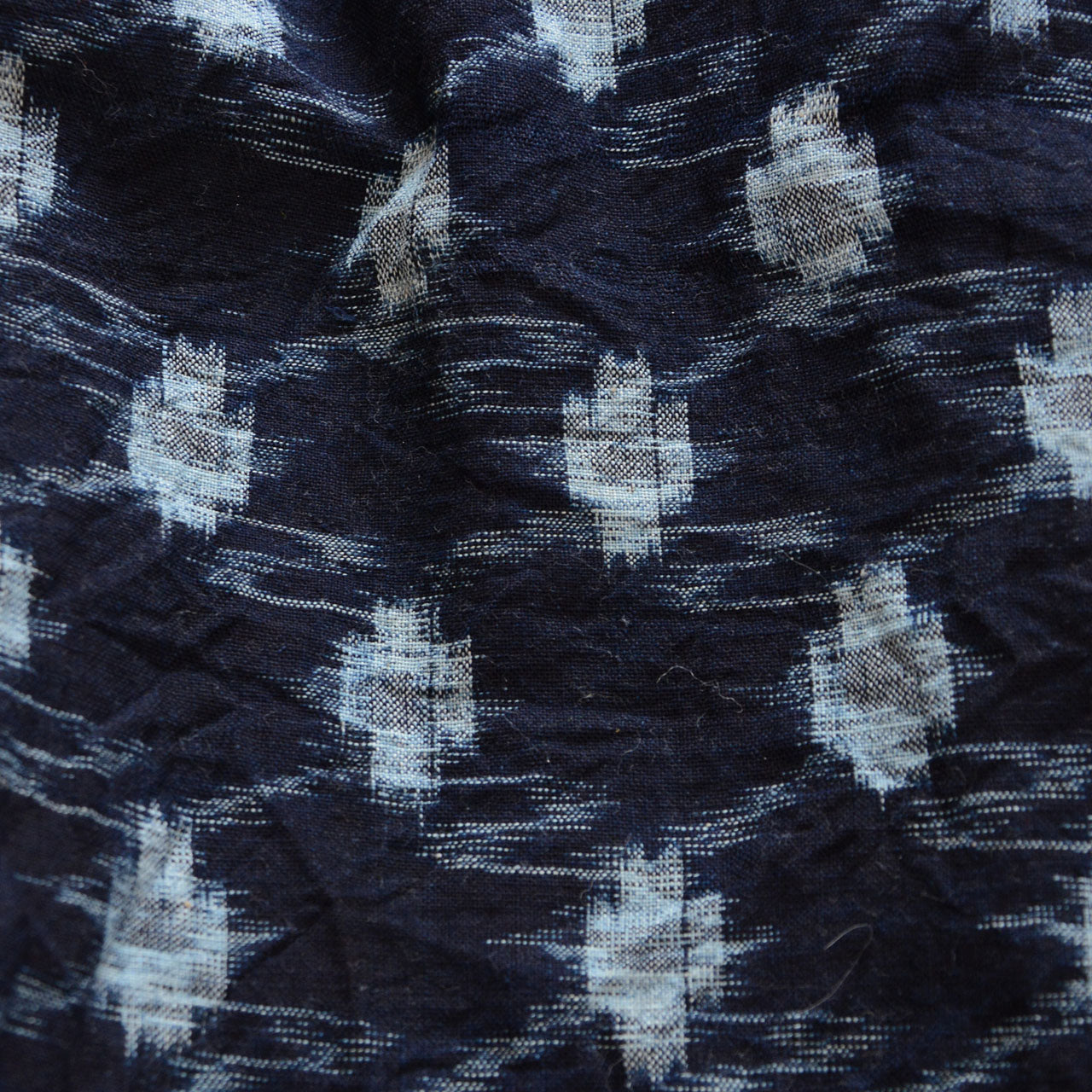 Close-up of indigo kasuri weave, navy cotton, light blue ikat pattern, aged texture, Showa era Japan vintage