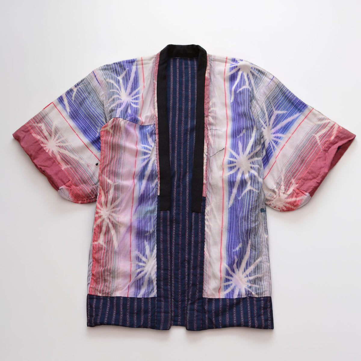 Reverse side of a Japanese vintage noragi jacket with colorful pink and blue starburst-patterned cotton panels and an indigo striped cotton center