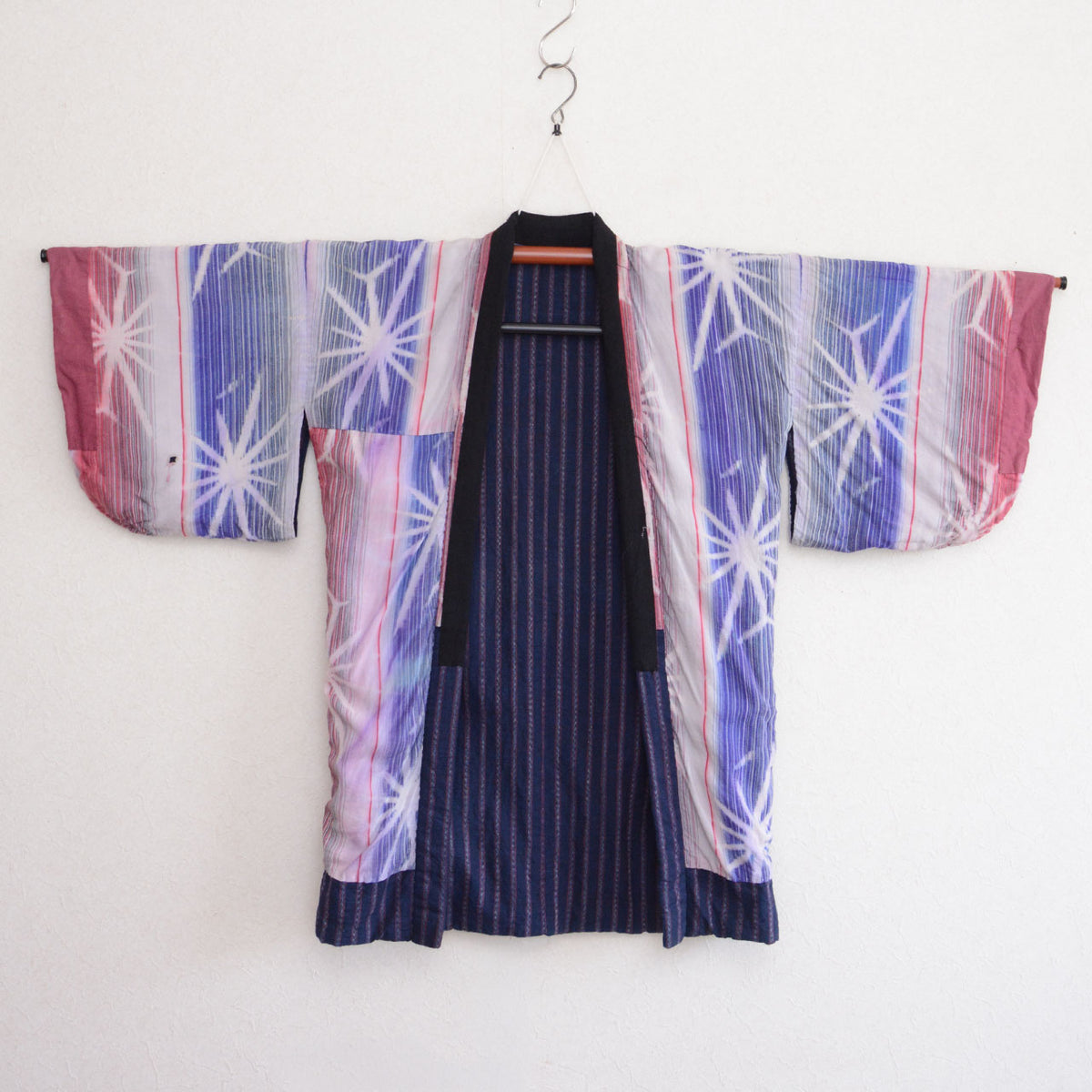 Reverse side of a Japanese vintage noragi jacket with colorful starburst-patterned cotton panels and an indigo striped cotton center