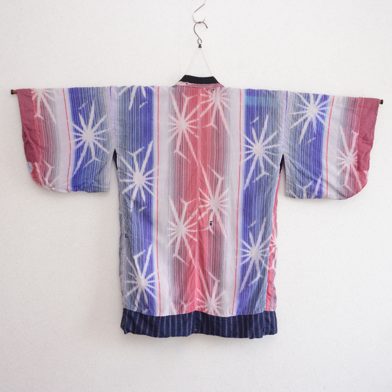 Back of a Japanese vintage noragi jacket in pink, blue, and white starburst-patterned cotton
