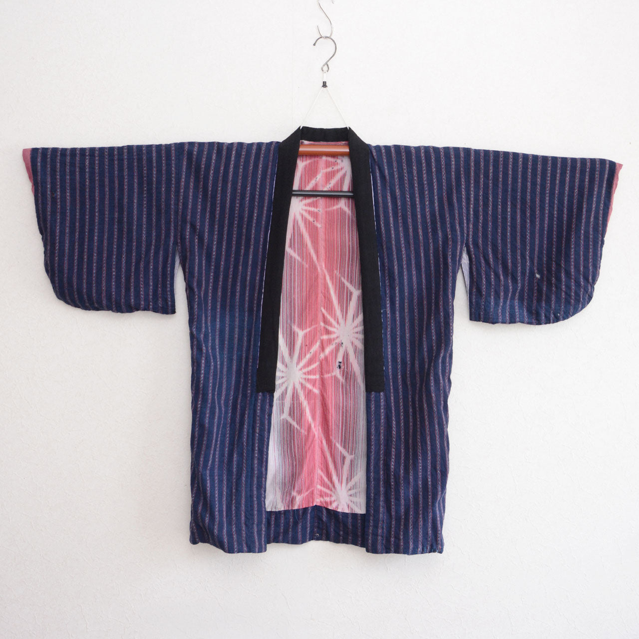 Front of a Japanese vintage noragi jacket with an indigo striped cotton body and a pink patterned center panel