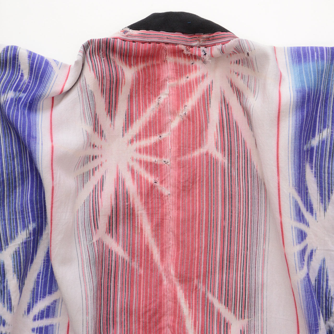 Close-up of white starburst motifs on blue and gray striped cotton panels of a Japanese vintage noragi jacket