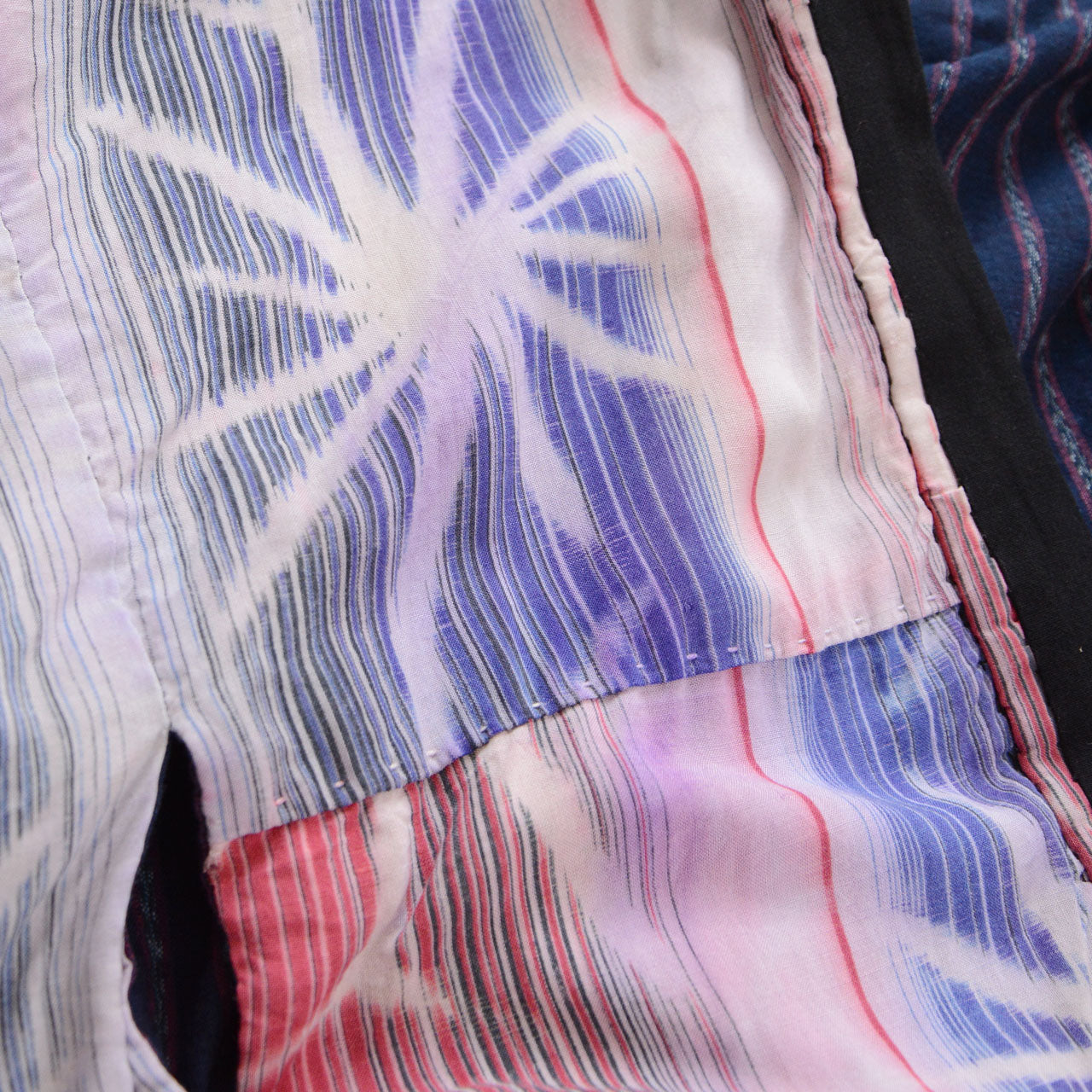 Close-up of pink and blue patterned cotton with holes, fraying, and color bleeding on a Japanese vintage noragi jacket