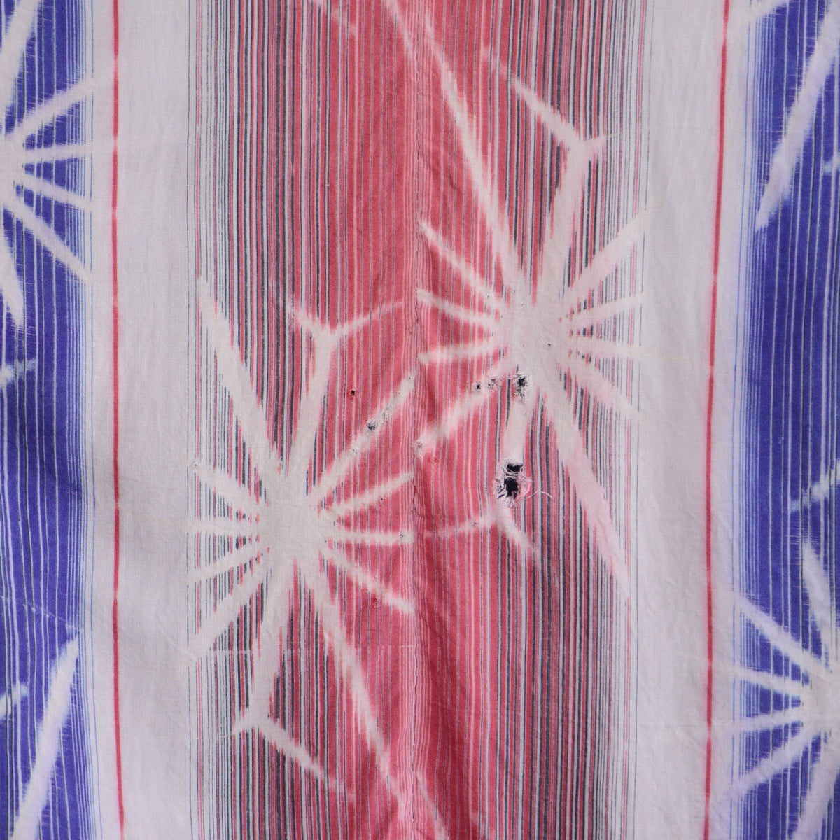Close-up of pink and blue patterned cotton with visible holes and fraying on a Japanese vintage noragi jacket