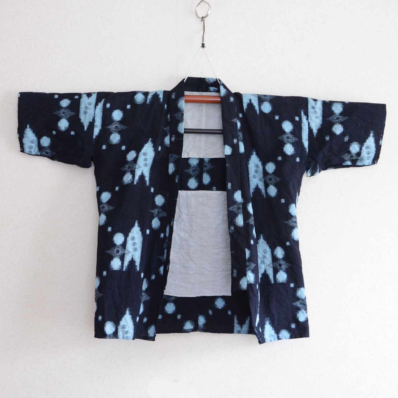 Vintage Japanese noragi jacket in indigo-dyed kasuri cotton, front view on hanger, geometric and dot kasuri pattern, mid-Showa era