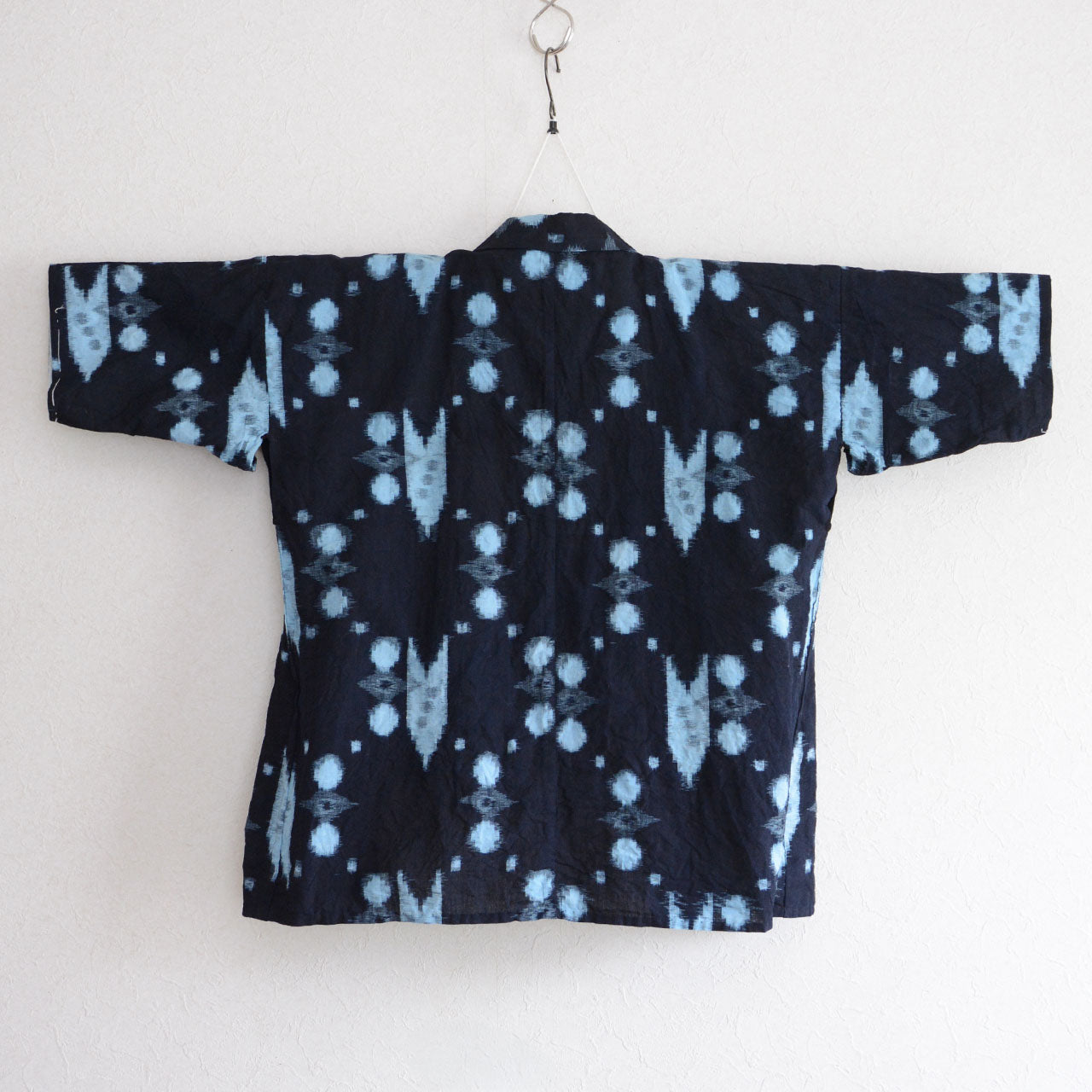 Vintage Japanese noragi jacket in indigo-dyed kasuri cotton, back view on hanger, full kasuri pattern visible, mid-Showa era