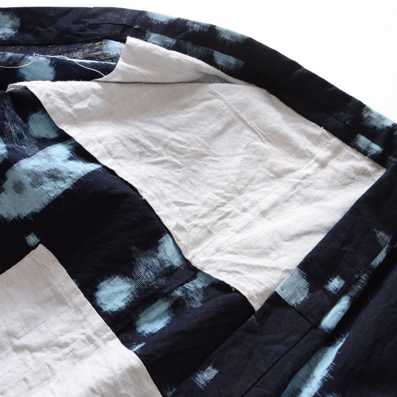 Interior detail of vintage Japanese noragi jacket showing hand-stitched cotton patch lining, indigo kasuri fabric