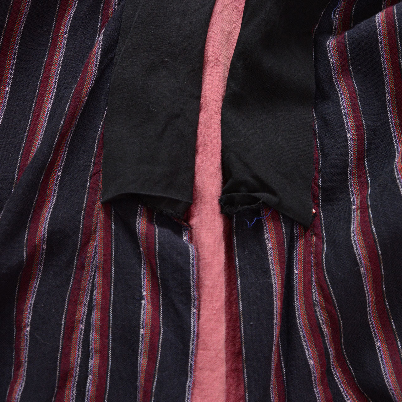 Japanese noragi showing the black front edging, salmon-pink lining, and worn striped outer fabric