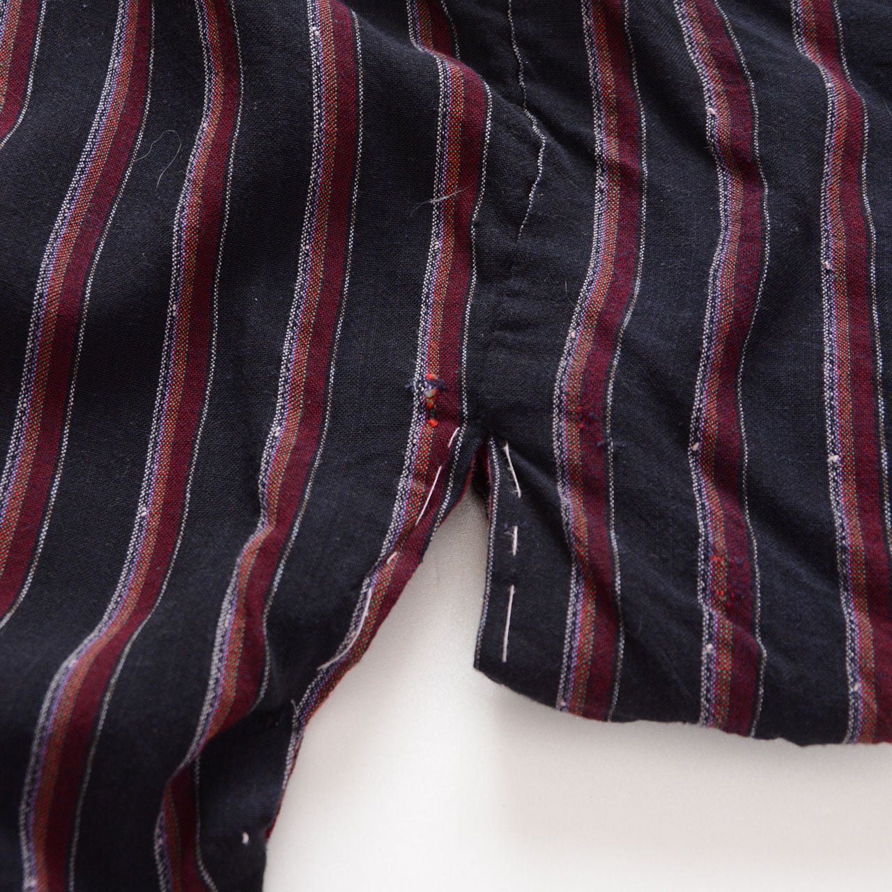 Boro repair with black patching and loose threads on a striped Japanese vintage noragi