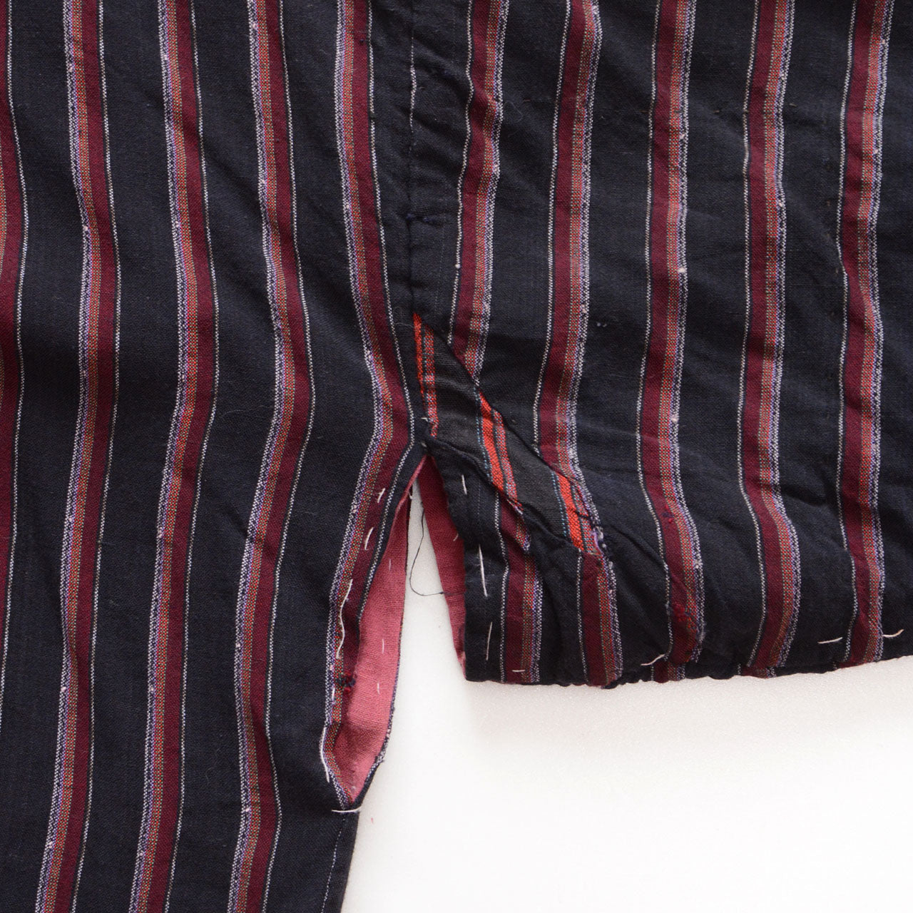 Miyatsuguchi opening with boro repairs, fraying, and a salmon-pink lining on a striped Japanese vintage noragi