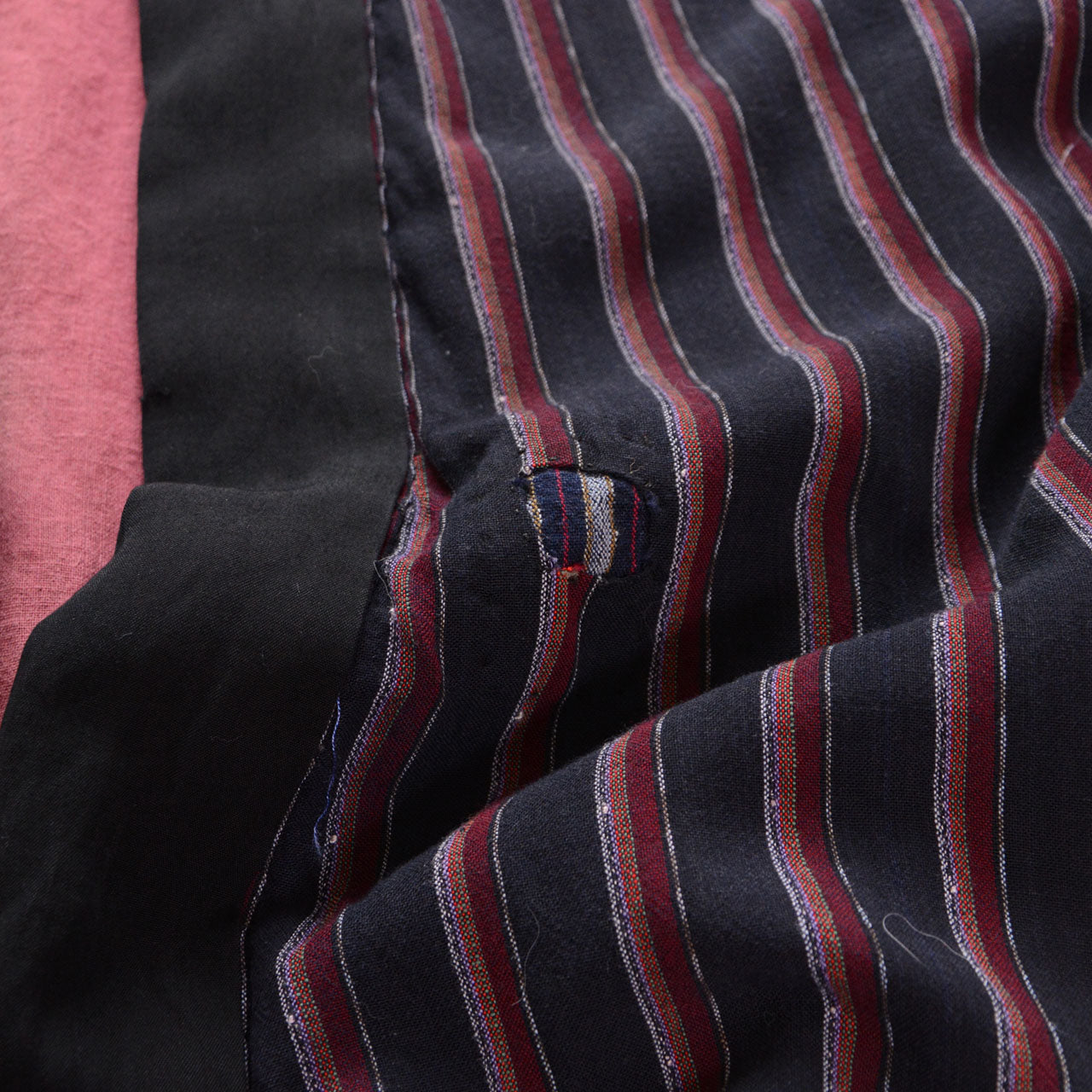 Collar-side boro repair, black front edging, salmon-pink lining, and striped outer fabric on a Japanese vintage noragi